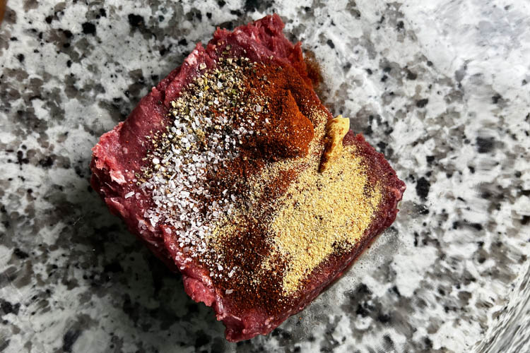 raw bison meat and seasoning on a marble board