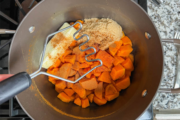 sweet potato ingredients in a bowl with a potato masher