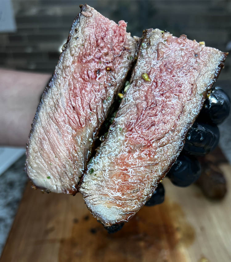 piece of new york strip steak cut in half to show doneness