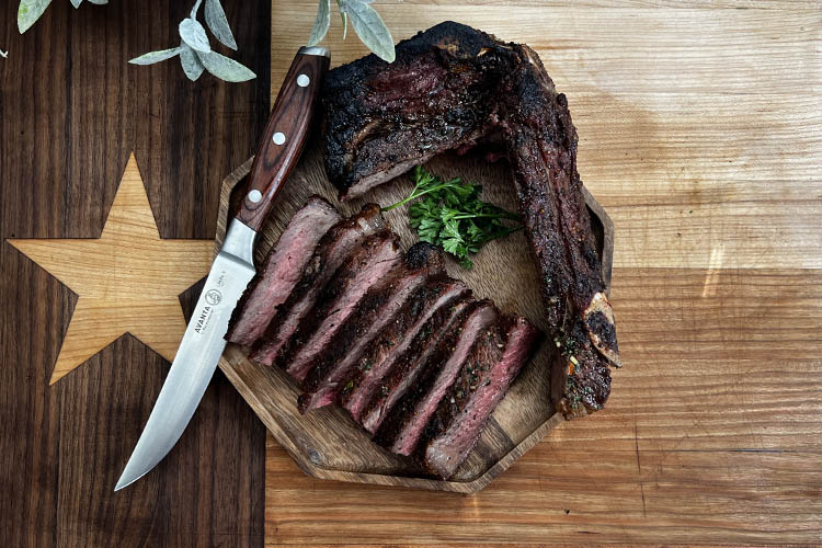 new york strip steak sliced on a wooden chopping board with a knife beside it