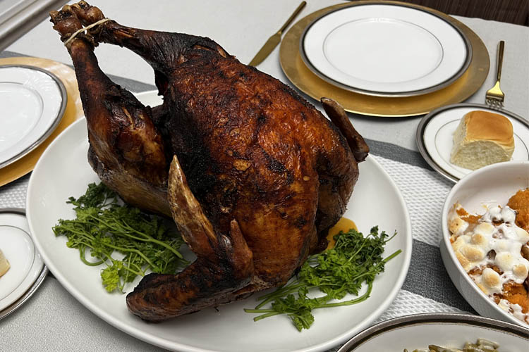 whole cooked turkey on a white plate with greenery