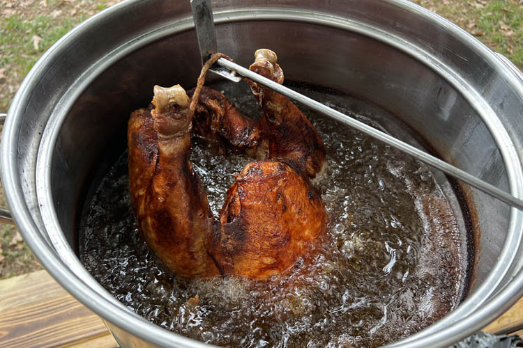 turkey half submerged into pot of hot oil