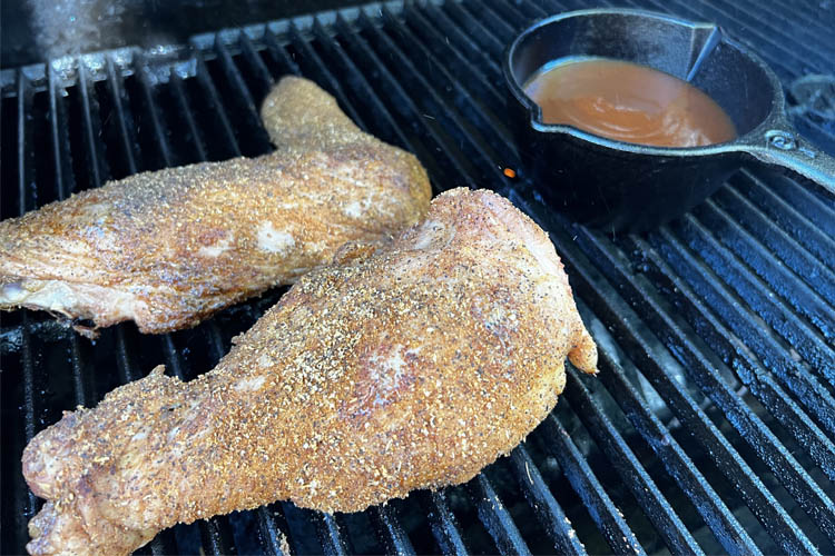turkey wings cooking on the grill with bowl of sauce in the background