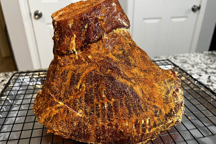 whole ham on wire rack with seasoning sprinkled on it