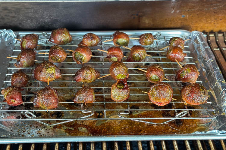 cooked bacon wrapped brussel sprouts on a wire tray in the smoker