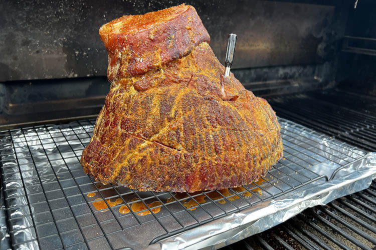 whole ham sitting on a wire rack with a temperature probe sticking out of it