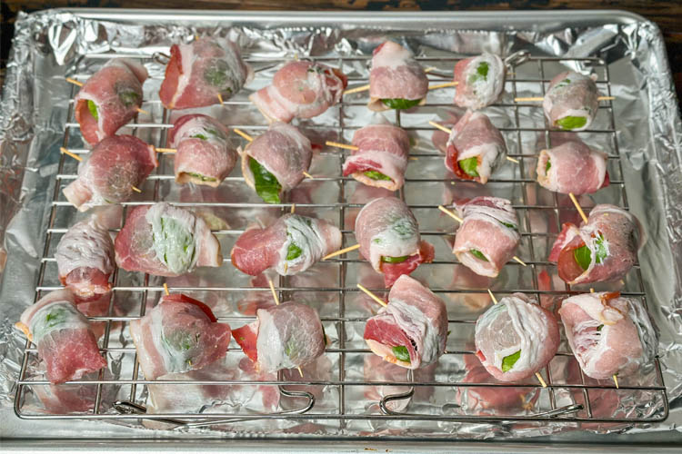 unseasoned bacon wrapped brussels sprouts on a wire rack over metal tray