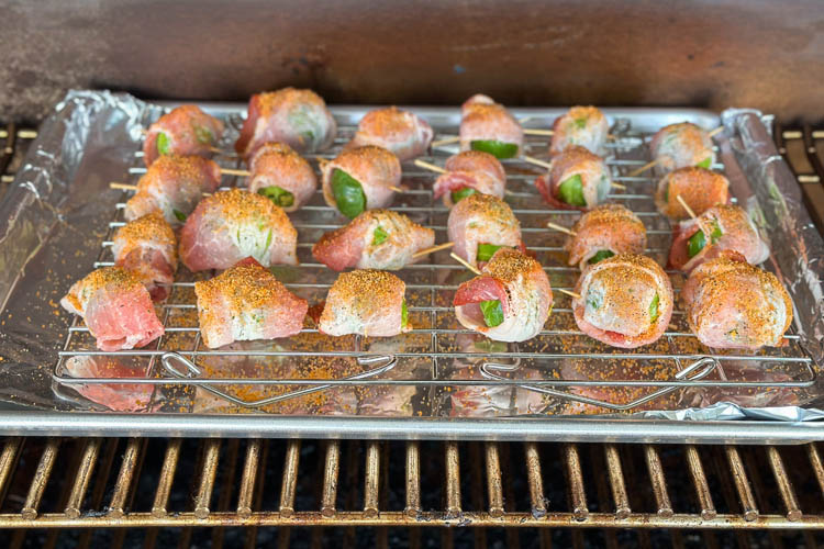 seasoned bacon wrapped brussels sprouts on a silver tray in the smoker