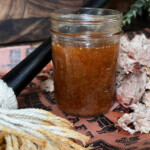 East Carolina mop sauce in a jar with mop in front and meat around it