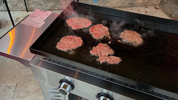 smashed burger patties cooking on a Victory propane gas griddle