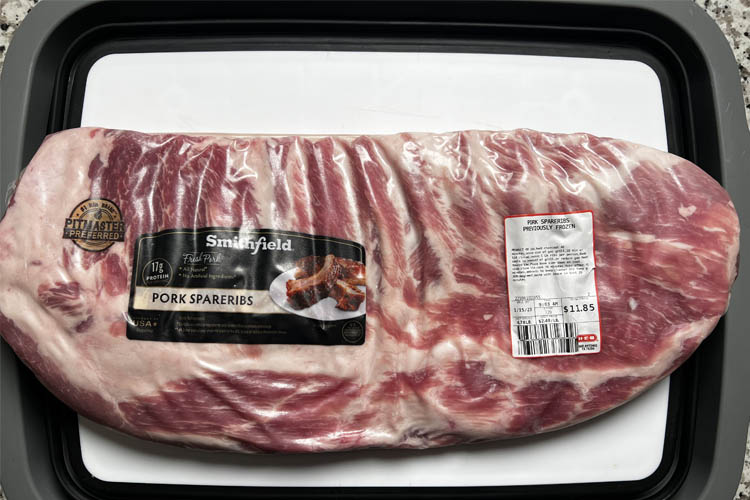 a rack of porkribs in packaging on a white plate