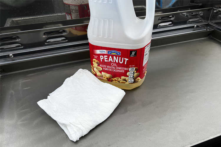 a bottle of peanut oil and cloth on griddle