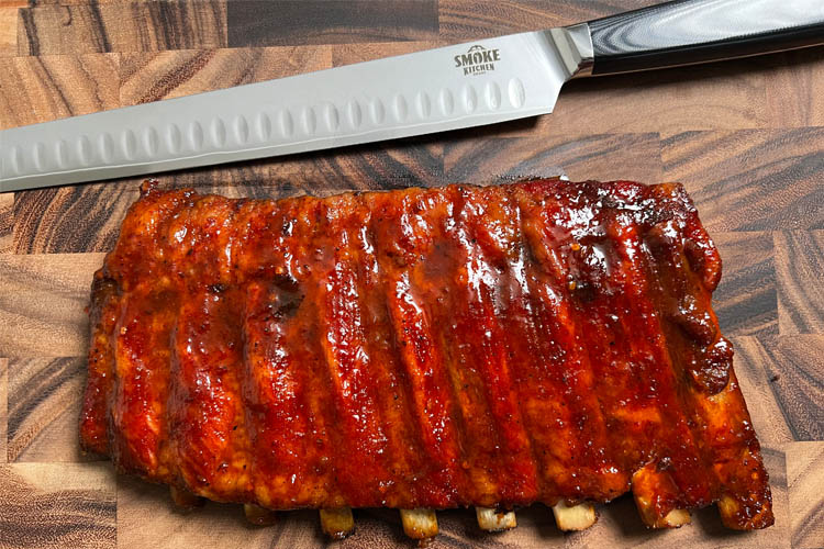 ribs on wooden chopping board with a smoke kitchen carving knife