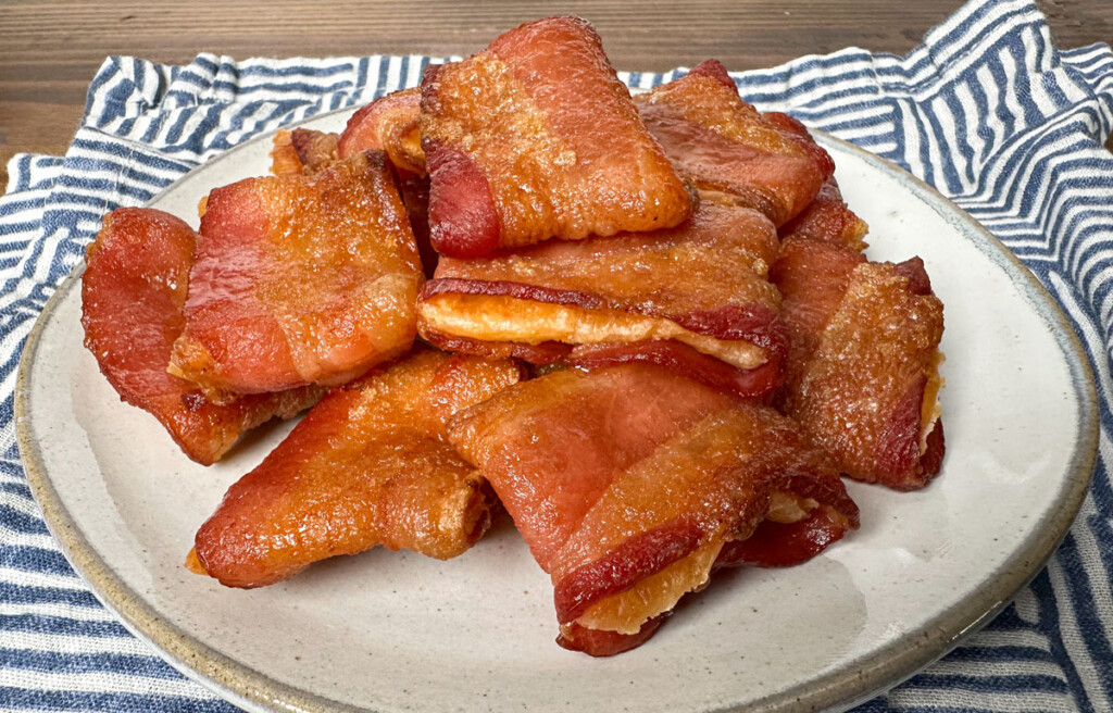 bacon wrapped crackers on a white plate