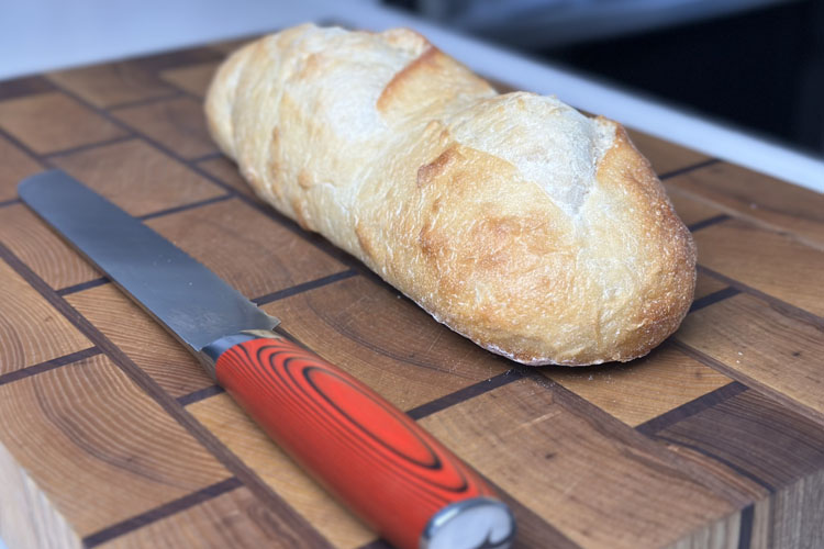french baguette and knife on wooden chopping board