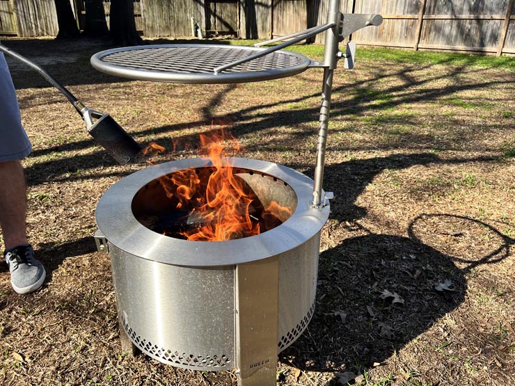 a person firing up the charcoal inside the Breeo Y Series fire pit with a torch
