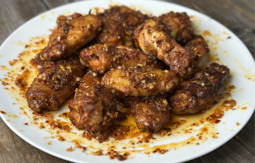 plate full of chicken wings with chili oil suace