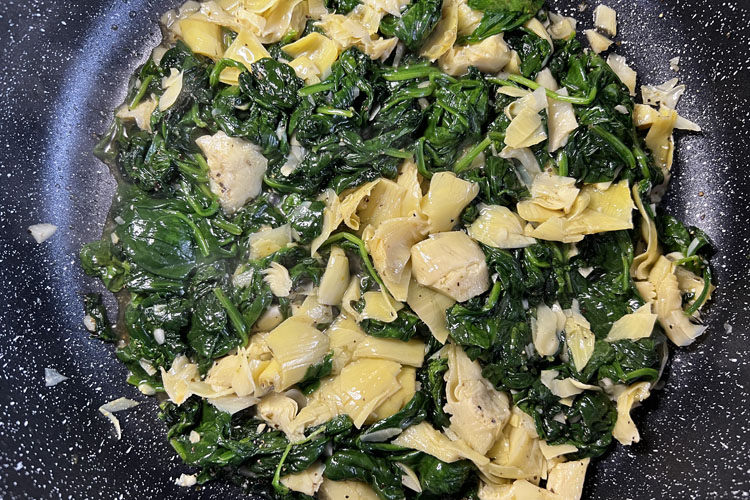cooked spinich and artichoke in a cast iron pot
