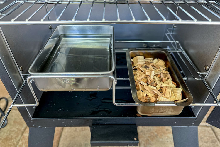 a tray of water and a tray of wood chips in an electric smoker