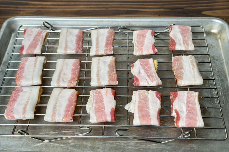 raw bacon wrapped crackers on a wire rack