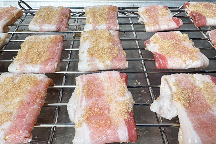 sugar coated raw bacon wrapped crackers on a wire rack