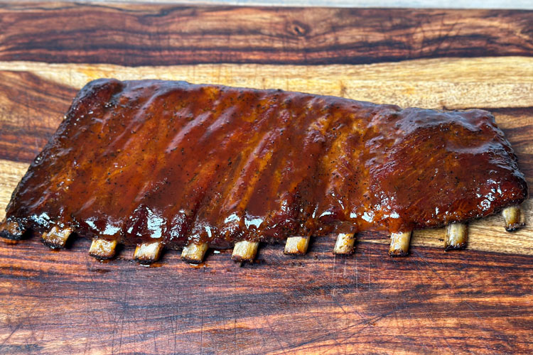 sauced up ribs on a wooden chopping board