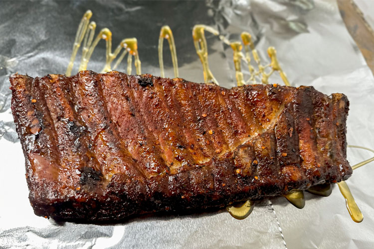ribs on aluminum foil with honey drizzled on it