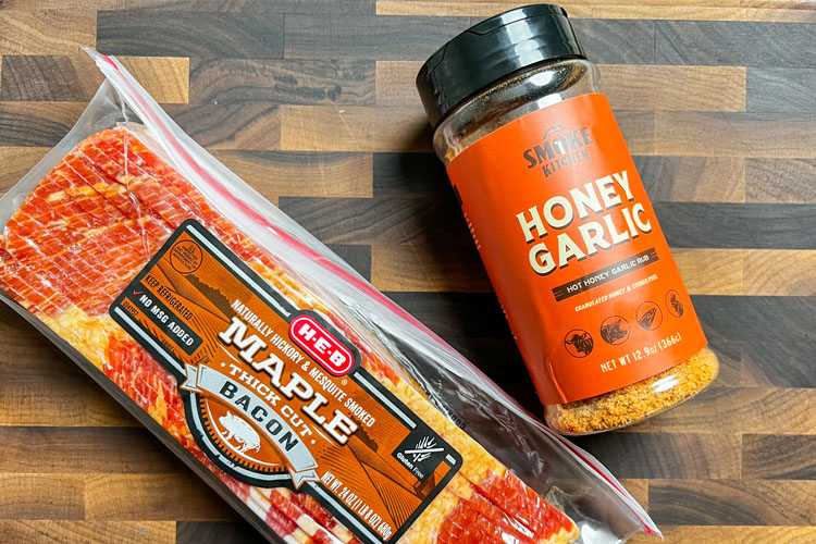 a jar of honey garlic rub and a pack of maple bacon on a wooden chopping board