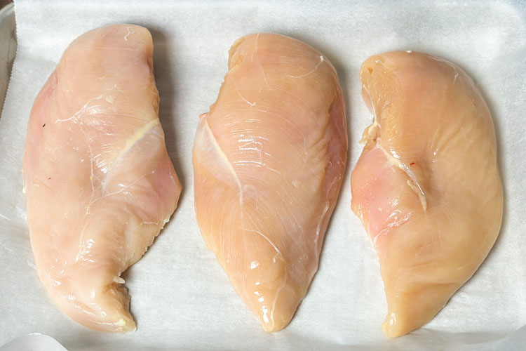 3 raw chicken breasts on white paper