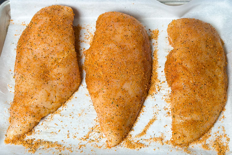 three seasoned chicken breasts on white paper