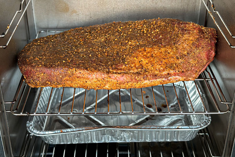 brisket in the electric smoker with aluminum tray underneath