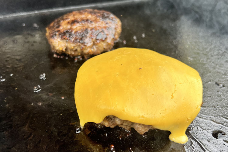 patty on the grill with cheese melting on top