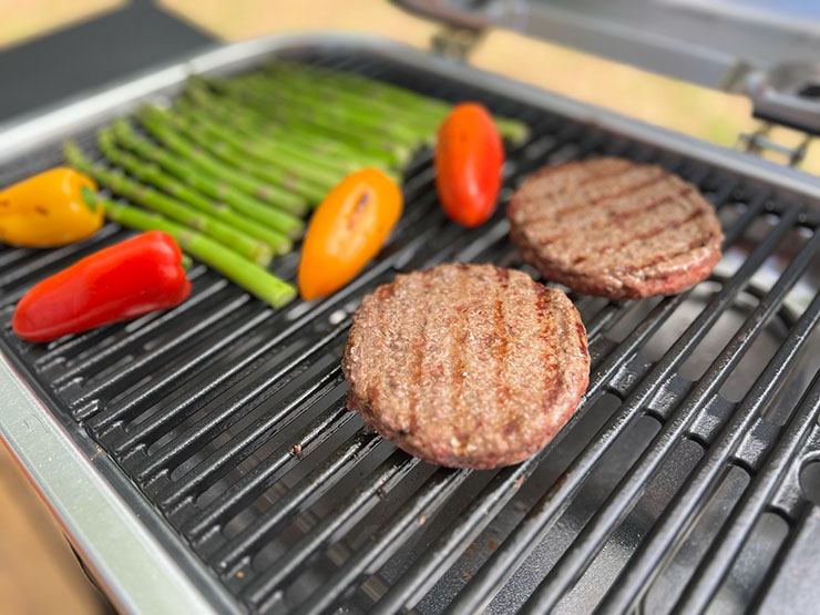 grilled burger patties and vegetables on Weber Lumin grill