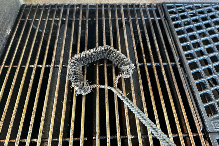 metal grill brush scrubbing the grates of grill