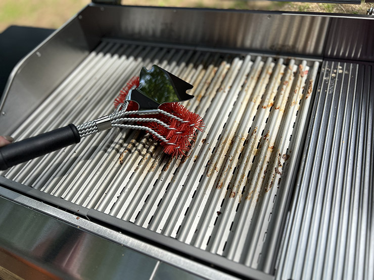 a grill brush on the stainless steel grill grates of the Char Broil Edge electric grill