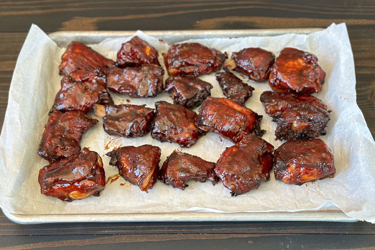 cooked rib tips on paper towels on a metal tray