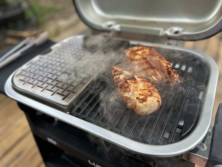 two chicken breasts smoking on the Weber Lumin electric grill