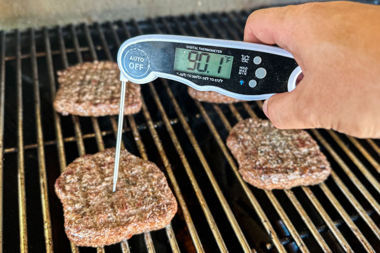 instant read thermometer in a burger on the grill