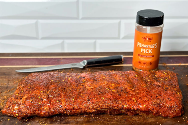 ribs on a wooden board with rub and a knife