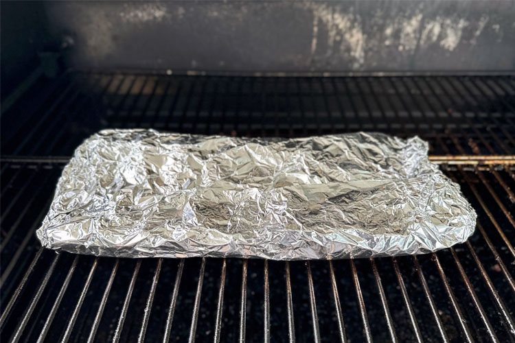 ribs wrapped in foil on the smoker