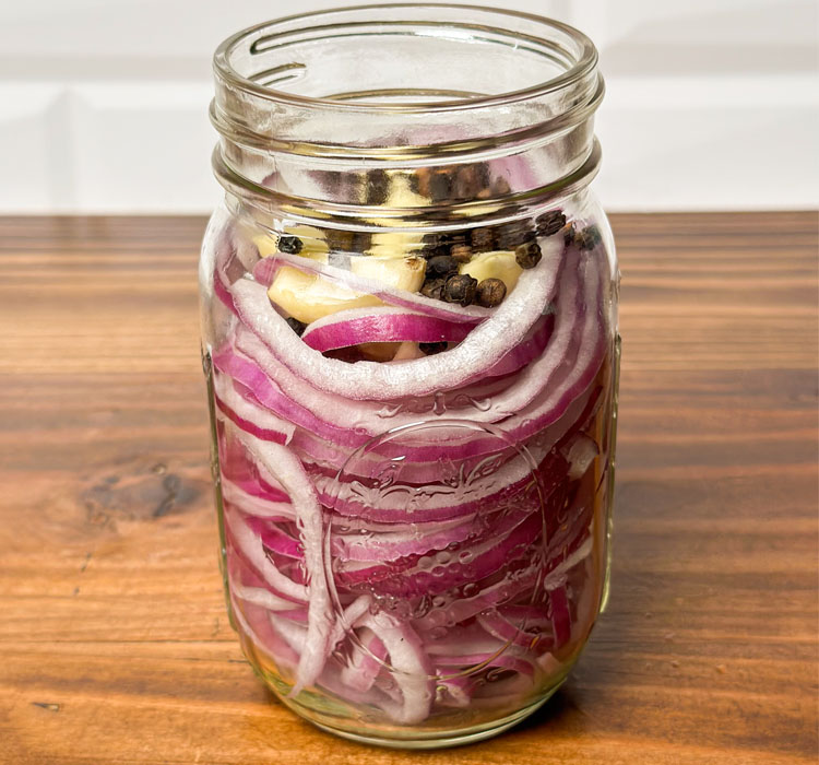 jar of sliced onions, garlic and peppercorns