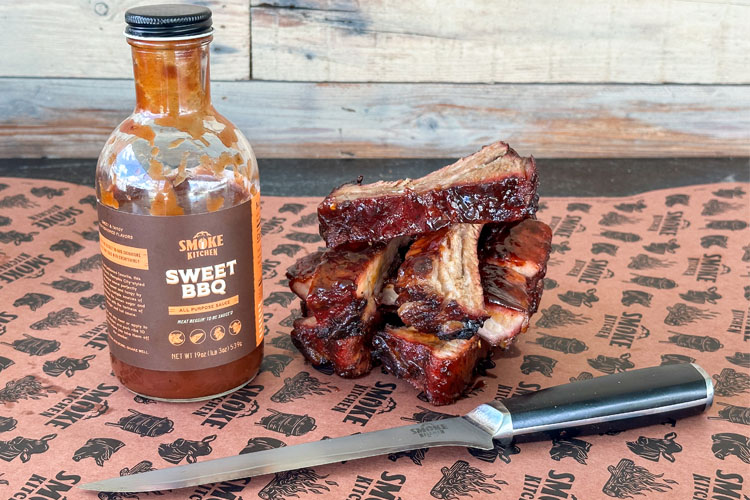 ribs, bbq sauce bottle and knife on smoke kitchen butchers paper
