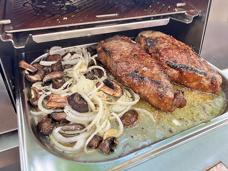 two new york strip steaks with mushrooms and onions cooked on the Schwank Infrared Grill