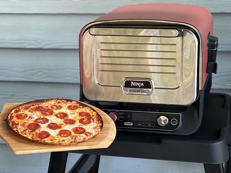 cooked pepperoni pizza next to a Ninja Woodfire Oven