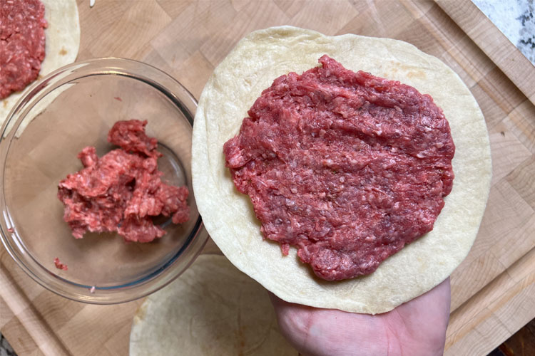 ground beef squished onto a flour tortilla