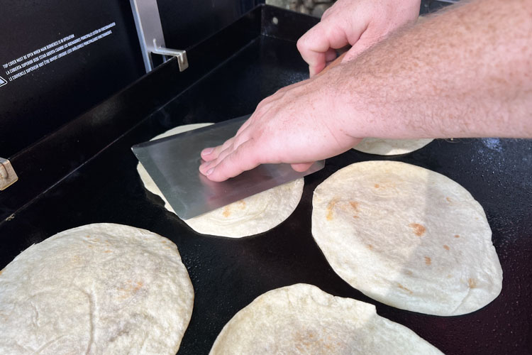 spatula being pushed down onto a flour tortilla