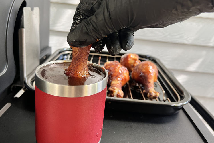 drumstick being dunked in a container of Smoke Kitchen Sweet BBQ sauce