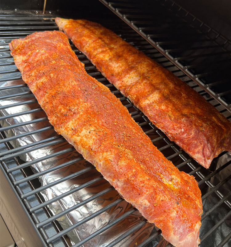 raw seasoned baby back ribs on the grill
