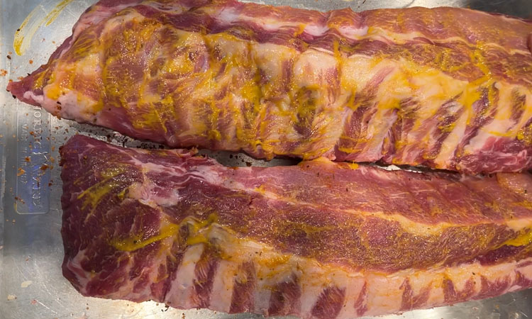 raw baby back ribs rubbed with mustard binder