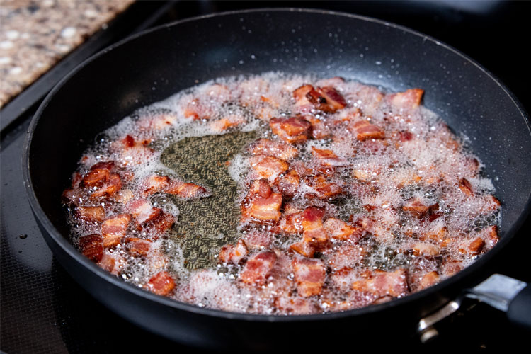 cooked bacon in a frypan of oil